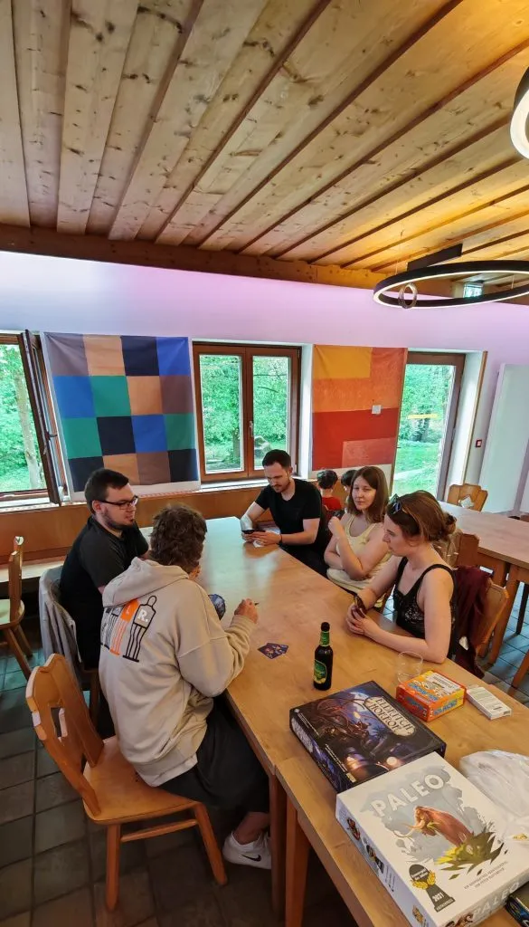 Große Spielrunde an einem langen Holztisch im Selbstversorgerhaus